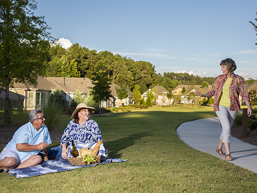 Neighbor waving to friends having a picnic in the community park.>